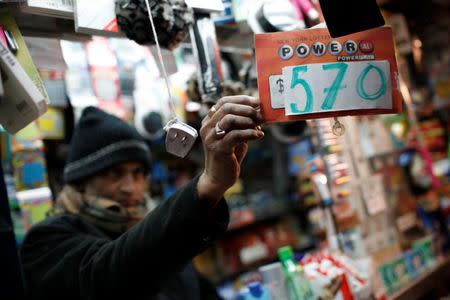 A vendor who sells lottery tickets hangs a sign for the Powerball drawing at a news stand in midtown Manhattan in New York City, New York, U.S., January 5, 2018. REUTERS/Mike Segar