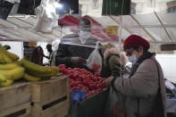 A woman wearing protective face masks as precaution against the conoravirus shops at an outdoor market in Paris, Friday, Oct. 30, 2020. France re-imposed a monthlong nationwide lockdown Friday aimed at slowing the spread of the virus, closing all non-essential business and forbidding people from going beyond one kilometer from their homes except to go to school or a few other essential reasons. (AP Photo/Thibault Camus)