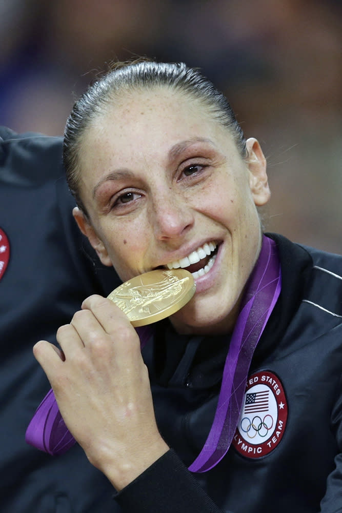 FILE - United States' Diana Taurasi bites her gold medal after beating France in the women's gold medal basketball game at the 2012 Summer Olympics, in London, in this Saturday, Aug. 11, 2012, file photo. Sue Bird and Diana Taurasi will try and become the first five-time Olympic gold medalists in basketball as they lead the U.S women's team at the Tokyo Games. The duo was selected for their fifth Olympics on Monday, June 21, 2021, joining Teresa Edwards as the only basketball players in U.S. history to play in five.(AP Photo/Charles Krupa, File)