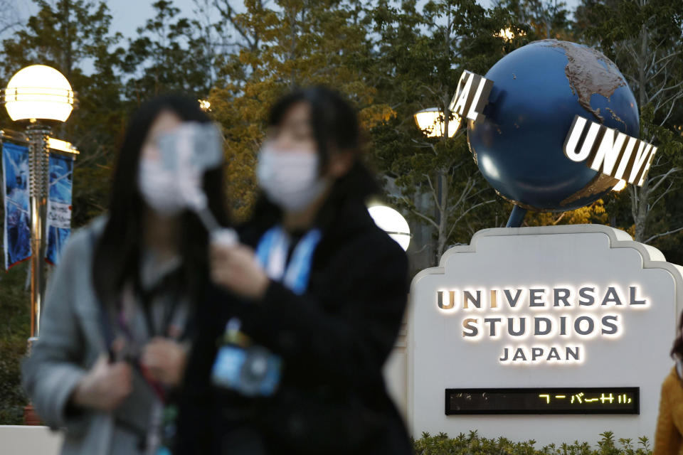 Visitors pose for a selfie in front of Universal Studios Japan in Osaka, western Japan Friday, Feb. 28, 2020. The theme park on Friday announced its temporary closure to prevent the spread of a new coronavirus. (Kyodo News via AP)