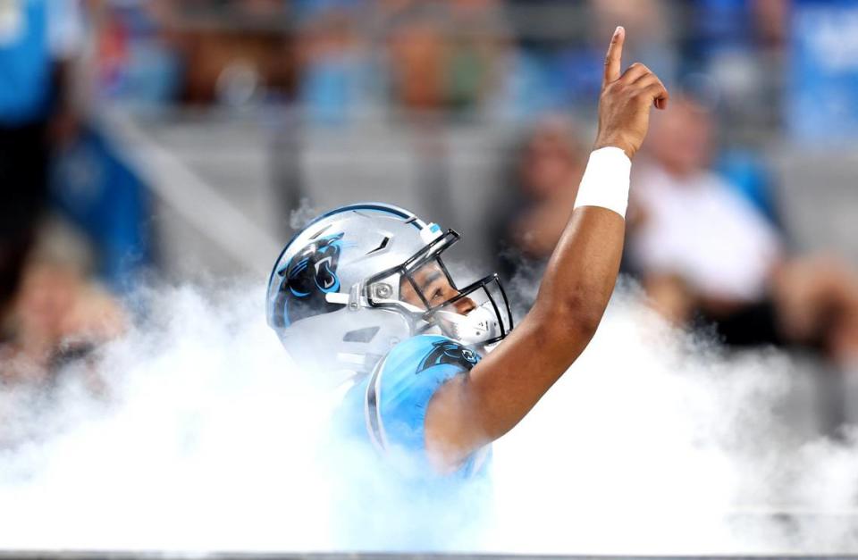 Carolina Panthers quarterback Bryce Young points skyward as he runs through the smoke onto the Bank of America Stadium field during player introductions on Friday, August 25, 2023.