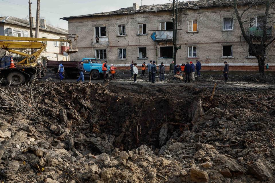 Local services workers remove debris near the crater, after a Russian missile strike at the site of damaged residential houses (REUTERS)