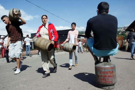 People carry gas cylinders at a distribution point San Cristobal, Venezuela August 3, 2017. Picture taken August 3, 2017. REUTERS/Luis Parada