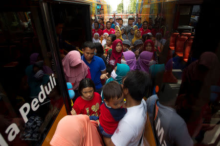 Residents jostle beside Suroboyo bus after exchanging plastic bottles for tickets at Purbaya station in Surabaya, Indonesia, October 21, 2018. REUTERS/Sigit Pamungkas/Files