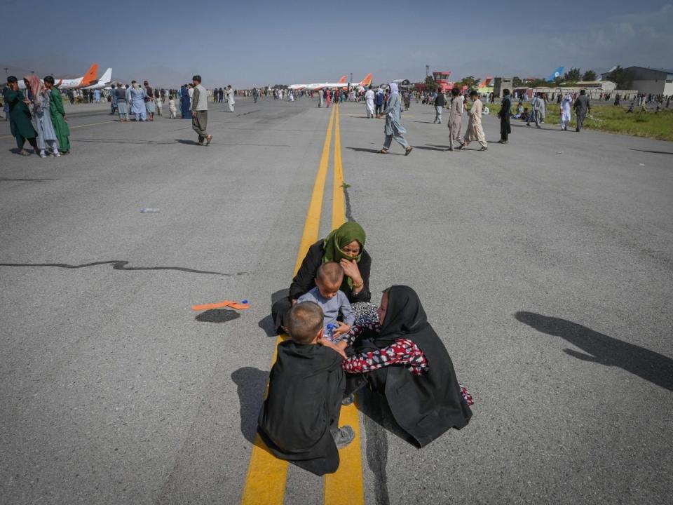 Afghan civilians sit on the airport tarmac in Kabul as they wait for a chance to leave Afghanistan on August 16, 2021. (Wakil Kohsar/AFP/Getty Images - image credit)