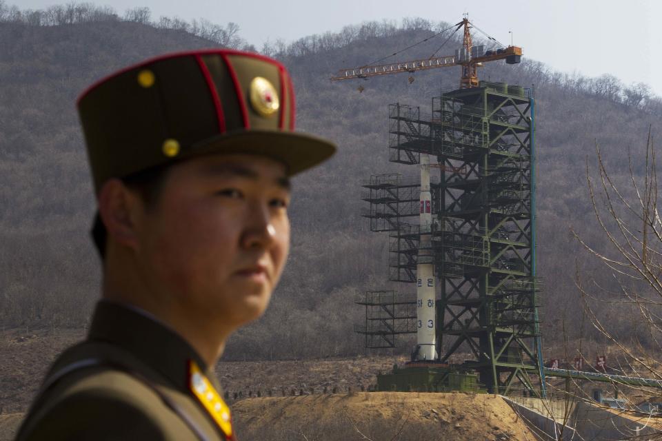 FILE - In this Sunday, April 8, 2012 file photo, a North Korean soldier stands in front of the country's Unha-3 rocket, slated for liftoff between April 12-16, at a launching site in Tongchang-ri, North Korea. According to North Korea's official version of things, commemorated on postage stamps and re-enacted in mass performances, the country's first venture into space was 14 years ago, when the "Bright Shining Star 1" satellite roared into orbit and began broadcasting marching music praising Kim Il Sung. (AP Photo/David Guttenfelder, File)