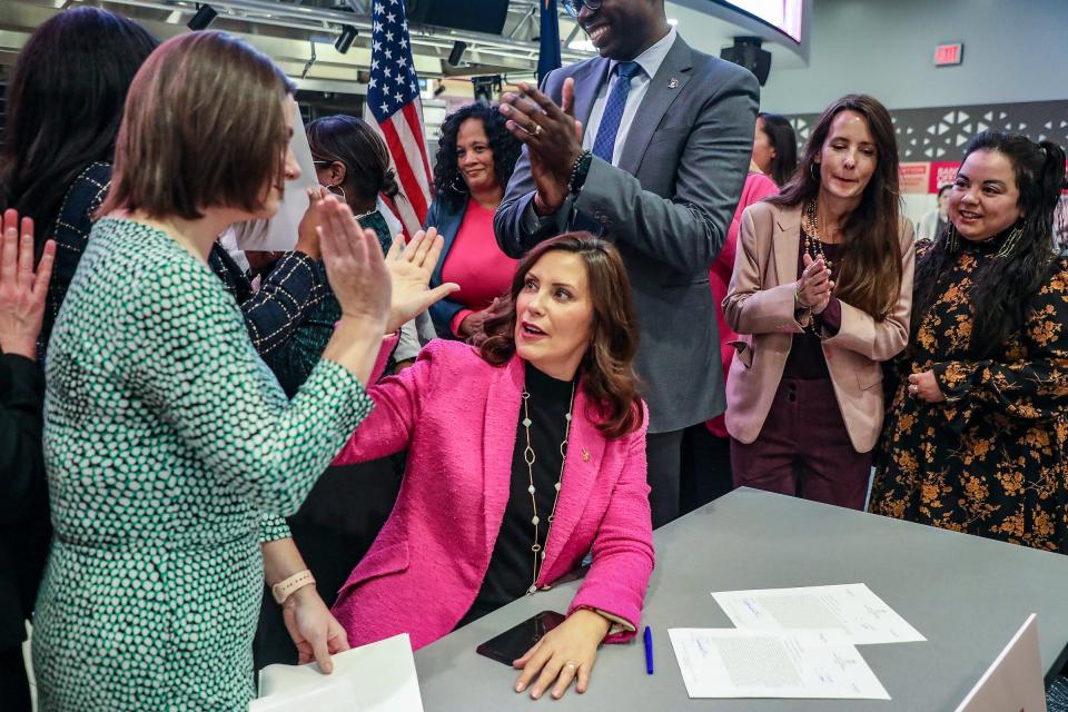 Michigan Gov. Gretchen Whitmer high-fives Michigan Rep. Lauren Pohutsky after signing of the Reproductive Freedom Act alongside lawmakers and activists who worked to get the legislation passed at Schoolcraft College in Livonia, Mich., on Tuesday, Nov. 21, 2023.