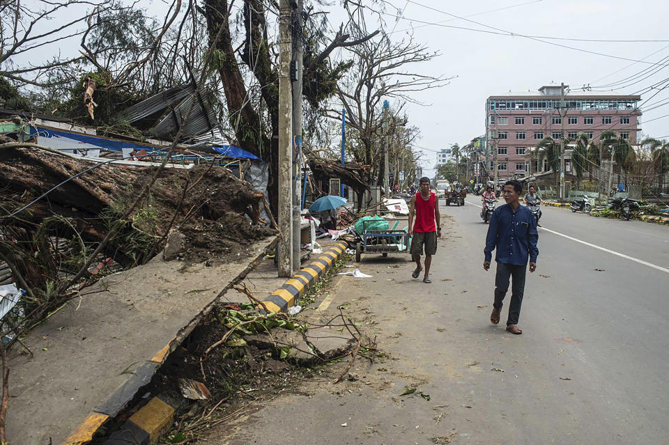 Local people walk past damaged buildings after Cyclone Mocha in Sittwe township, Rakhine State, Myanmar, Monday, May 15, 2023. Rescuers on Monday evacuated about 1,000 people trapped by seawater 3.6 meters (12 feet) deep along western Myanmar's coast after the powerful cyclone injured hundreds and cut off communications. (AP Photo)