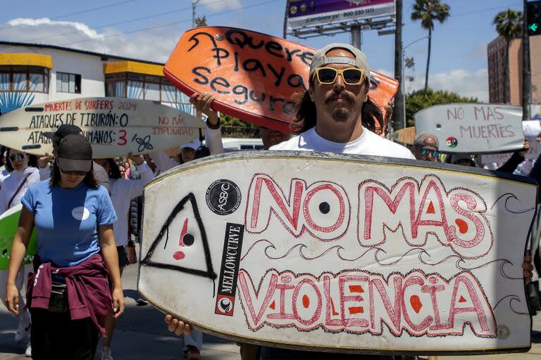 Un manifestante sosteniendo un bodyboard escrito en español 