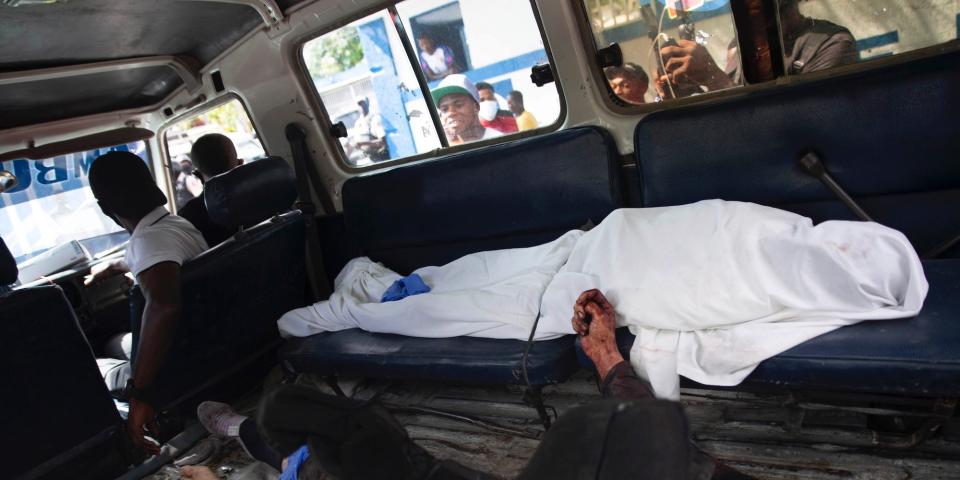Two bodies, one shrouded and the other just out of view, in the back of a van. Haitian police say they are suspects in the killing of Jovenel Moïse.