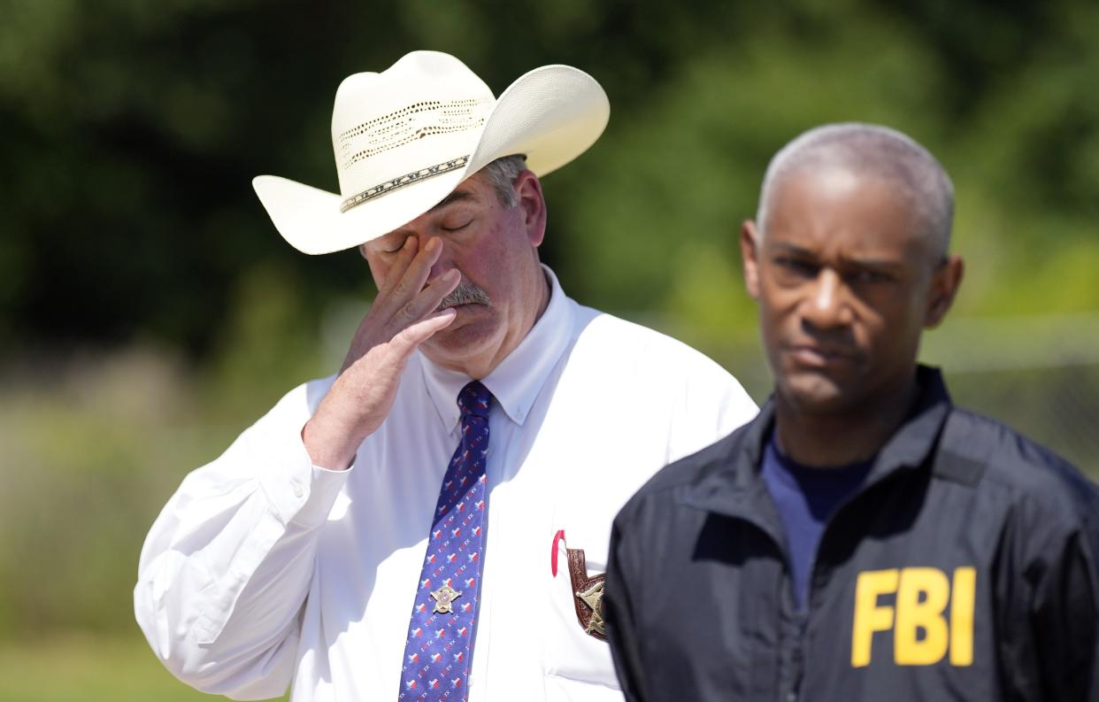 San Jacinto County Sheriff Greg Capers, left, wipes his eye as FBI Houston Special Agent in Charge James Smith speaks during a news conference, Sunday, April 30, 2023, in Cleveland, Texas. The search for a Texas man who allegedly shot his neighbors after they asked him to stop firing off rounds in his yard stretched into a second day Sunday, with authorities saying the man could be anywhere by now. The suspect fled after the shooting Friday night that left five people dead, including an 8-year-old boy. (AP Photo/David J. Phillip)