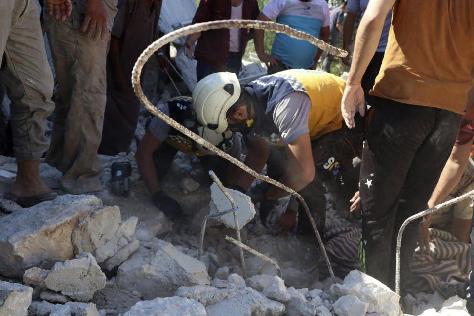 This photo provided by the Syrian Civil Defense White Helmets, which has been authenticated based on its contents and other AP reporting, shows a Syrian White Helmet civil defense worker digging in the rubble of destroyed house that hit by Syrian government rockets, in Ibleen village, southern Idlib province, Syria, Thursday, July 15, 2021. At least eight civilians were killed, including three children, when Syrian government rockets hit two villages in the last rebel stronghold in Idlib province, rescue workers and a war monitor said Thursday. (Syrian Civil Defense White Helmets via AP)