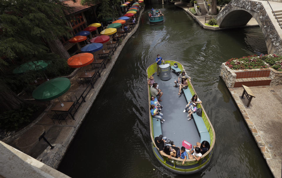 Using social distancing and other protective measures against COVID-19, visitors ride a river barges along the River Walk in San Antonio, Monday, June 15, 2020, in San Antonio. The barges, which have been closed due to the COVID-19 pandemic, began running again Monday. (AP Photo/Eric Gay)