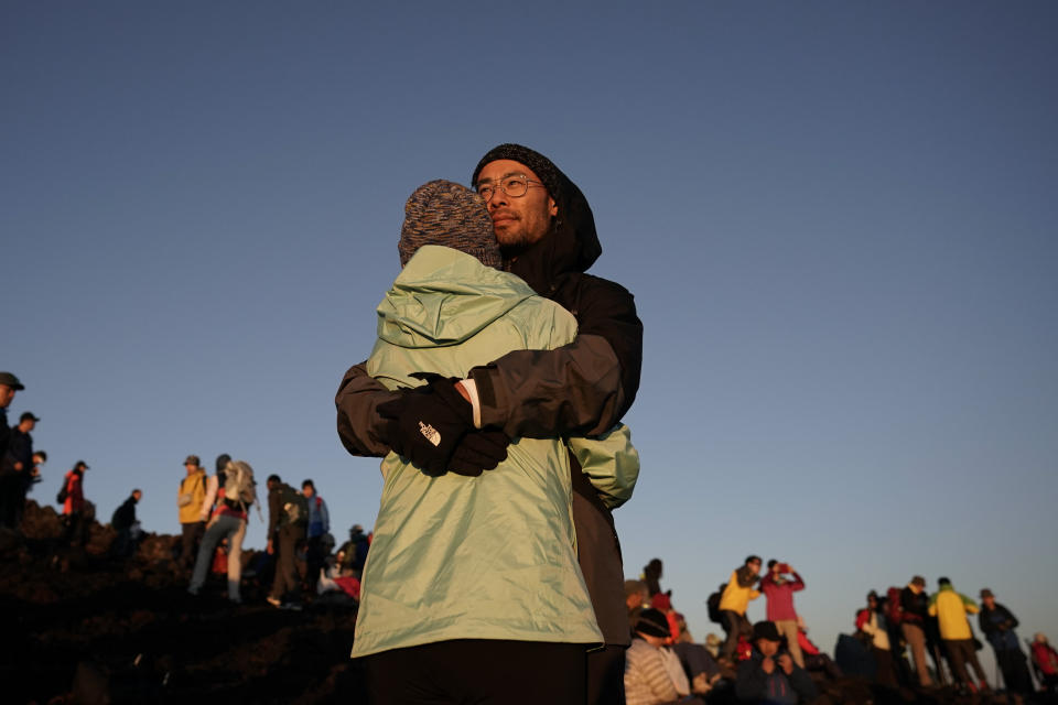 A couple embraces while watching the sunrise from the summit of Mount Fuji, Saturday, Aug. 3, 2019, in Japan. People come from all over Japan to climb to the summit to see the sun rise. (AP Photo/Jae C. Hong)