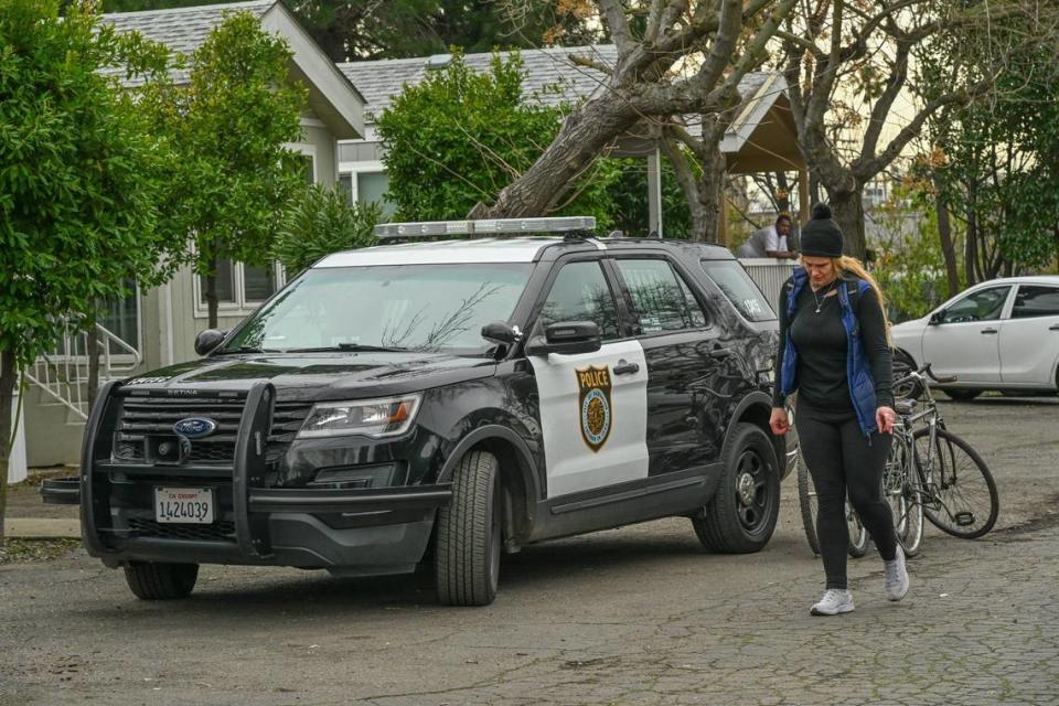 Jessica Rose pasa junto a sus bicicletas y un vehículo de la policía de Sacramento después de tirar algunas de sus pertenencias a la basura mientras era desalojada con su hija de 11 años y su esposo en febrero. Le permitieron guardar algunos objetos en la propiedad durante tres semanas hasta que pudiera ahorrar suficiente dinero para conseguir una unidad de almacenamiento.