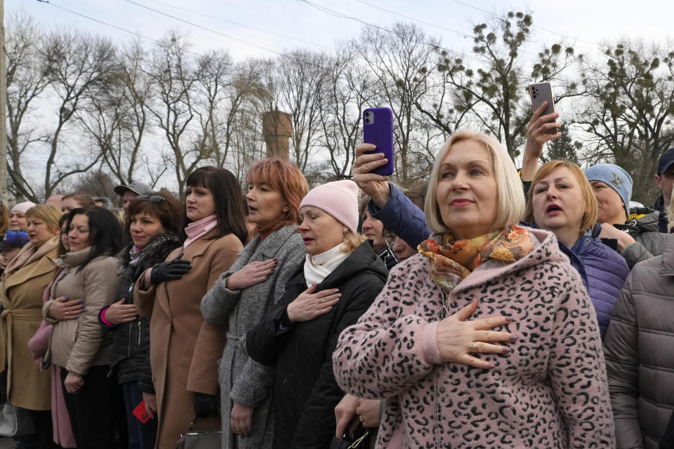 People sing the national anthem during a visit by Ukrainian President Volodymyr Zelenskyy to Okhtyrka in the Sumy region of Ukraine, Tuesday March 28, 2023. A team of journalists from The Associated Press traveled with Zelenskyy aboard his train for two nights as he visited troops along the front lines and communities that have been liberated from Russian control. Zelenskyy is hoping his trips keep the public's attention on the war, particularly in parts of Ukraine where life can often appear to have returned to normal. (AP Photo/Efrem Lukatsky)