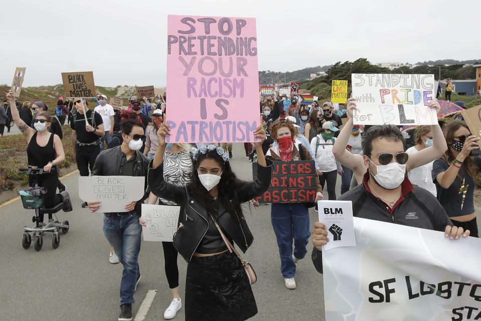 Sarzana Khan, center, and Gabriel Reyla, right, march with gay activists and suppoters on the Great Highway at Ocean Beach in San Francisco, Sunday, June 14, 2020, at a protest over the Memorial Day death of George Floyd, who died after being restrained by Minneapolis police. (AP Photo/Jeff Chiu)