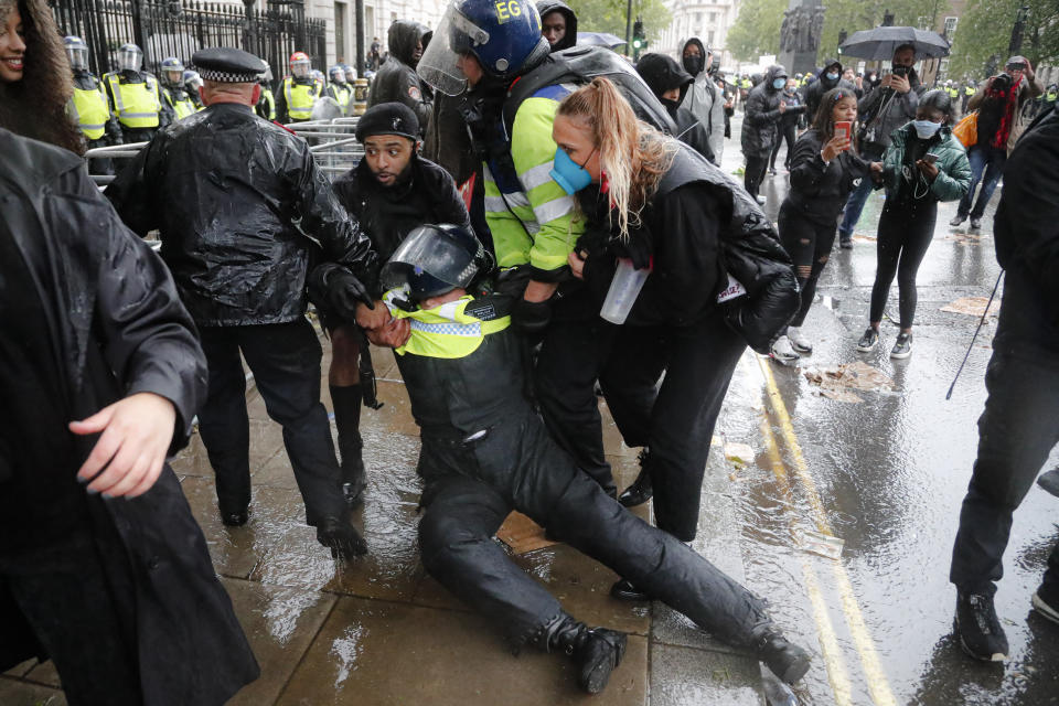A police officer who was injured when falling of a horse during scuffles with demonstrators at Downing Street during a Black Lives Matter march in London, Saturday, June 6, 2020, is dragged by colleagues, as people protest against the killing of George Floyd by police officers in Minneapolis, USA. Floyd, a black man, died after he was restrained by Minneapolis police while in custody on May 25 in Minnesota. (AP Photo/Frank Augstein)