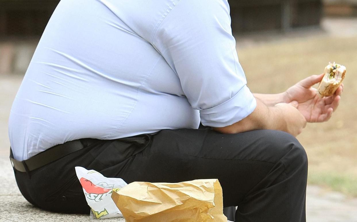 Overweight man eating a sandwich