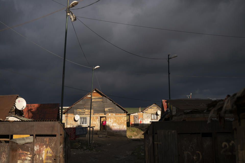 In this Nov. 14, 2018, photo, a Roma woman stands at the entrance of her house as dark clouds hover over the Podhorany village near Kezmarok, Slovakia. An investigation by The Associated Press has found that women and their newborns in Slovakia are routinely, unjustifiably and illegally detained in hospitals across the European Union country. Roma women, vulnerable to racist abuse and physical violence, suffer particularly. They’re also often poor, and mothers who leave hospitals before doctors grant permission forfeit their right to a significant government childbirth allowance of several hundred euros. (AP Photo/Felipe Dana)