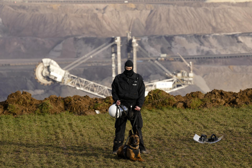 A police officer guards the demolition edge of the open pit mine Garzweiler at the village Luetzerath near Erkelenz, Germany, Wednesday, Jan. 11, 2023. Police have entered the condemned village in launching an effort to evict activists holed up at the site in an effort to prevent its demolition to make way for the expansion of a coal mine. (AP Photo/Michael Probst)