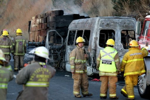 Firefighters and forensic medical personnel work at the scene of an accident between a tourist van and a cargo truck on the Lagos de Moreno highway in Zapotlanejo, Jalisco State, Mexico