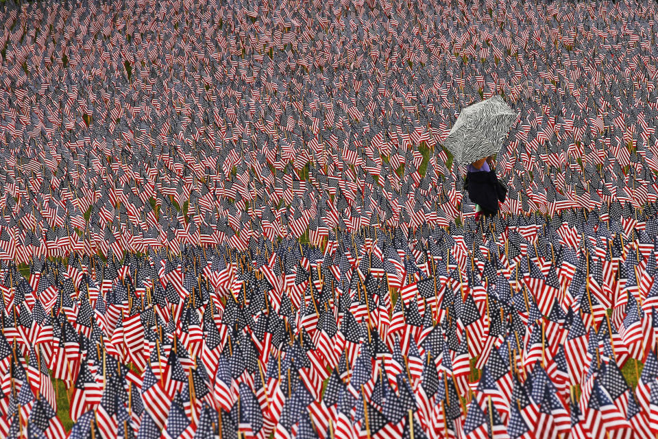 A pedestrian carrying an umbrella walks through a Memorial Day display of United States flags on the Boston Common in Boston, Massachusetts, on May 23, 2013.