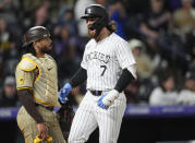 Colorado Rockies' Brendan Rodgers crosses home plate after hitting a grand slam, next to San Diego Padres catcher Luis Campusano during the fourth inning of a baseball game Tuesday, April 23, 2024, in Denver. (AP Photo/David Zalubowski)