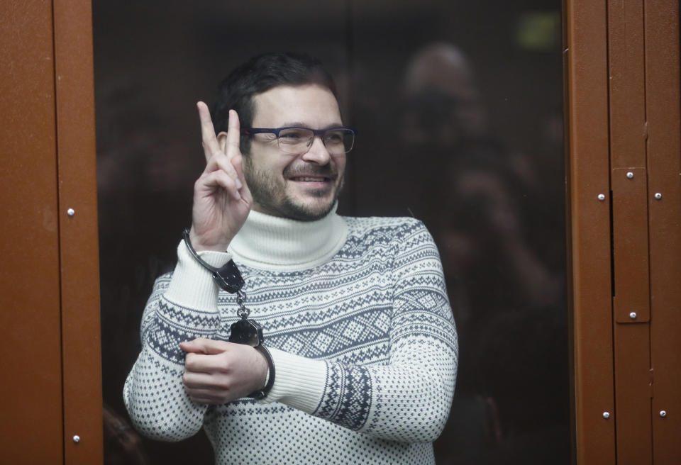 Russian opposition activist and former municipal deputy of the Krasnoselsky district Ilya Yashin gestures, smiling as he stands inside a glass cubicle in a courtroom, prior to a hearing in Moscow, Russia, Friday, Dec. 9, 2022. Yashin faces a trial on charges stemming from his criticism of the Kremlin's action in Ukraine. (Yury Kochetkov/Pool Photo via AP)