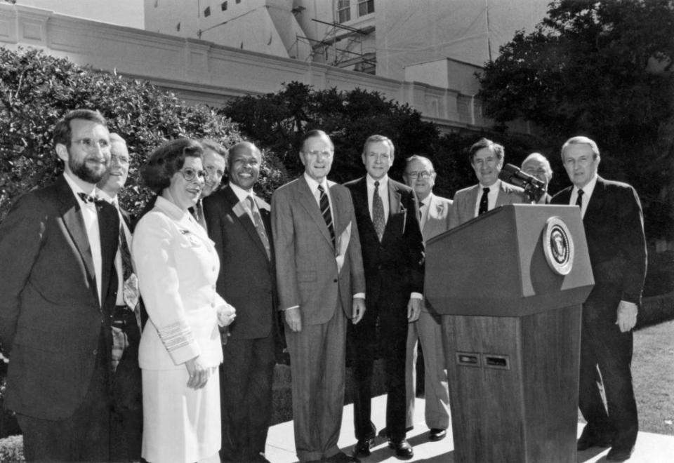 Novello and men surrounding a podium