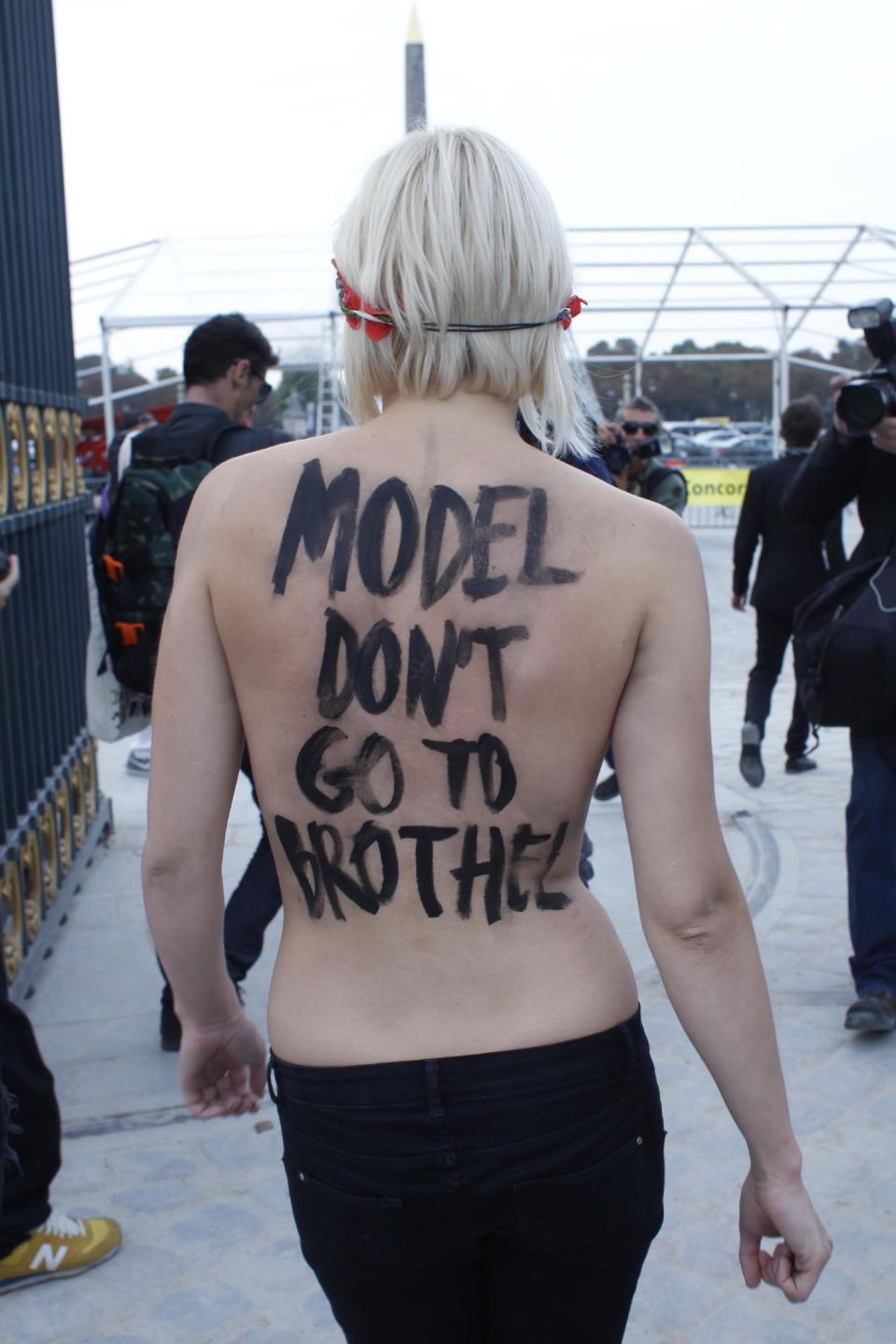 An activist of Femen, a feminist Ukrainian protest group, leaves the Tuileries Gardens after two of them were removed by security staff while disturbing the presentation of Nina Ricci's ready-to-wear Spring/Summer 2014 fashion collection Thursday, Sept. 26, 2013 in Paris. (AP Photo/Thibault Camus)