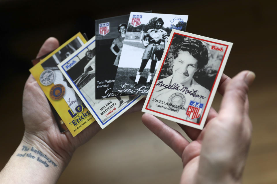 In this April 30, 2020, photo, Anika Orrock holds some of her autographed baseball cards of players from the All-American Girls Baseball League at her home in Nashville, Tenn. Orrock has written and illustrated a book on the players titled "The Incredible Women of the All-American Girls Professional Baseball League." (AP Photo/Mark Humphrey)