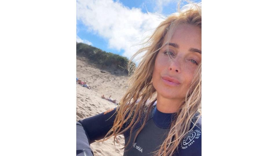 woman sitting on beach in wetsuit 