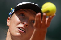 Poland's Iga Swiatek, who plays with a ribbon in the colors of the Ukraine flag on her cap, left, serves against Montenegro's Danka Kovinic during their third round match at the French Open tennis tournament in Roland Garros stadium in Paris, France, Saturday, May 28, 2022. (AP Photo/Michel Euler)