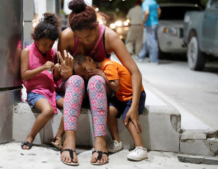 Fransisca Sislavas sits next to her daughter Brittany and her son Rony near the vehicle after an unidentified gunman killed her husband in a taxi in San Pedro Sula, Honduras, July 26, 2018. REUTERS/Goran Tomasevic