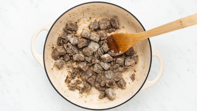 Beef chunks and flour cooking in casserole pot