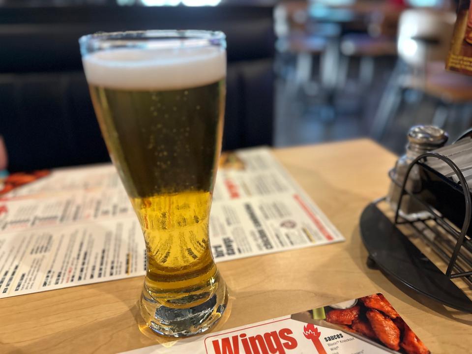 Tall glass of hard cider on table at buffalo wild wings