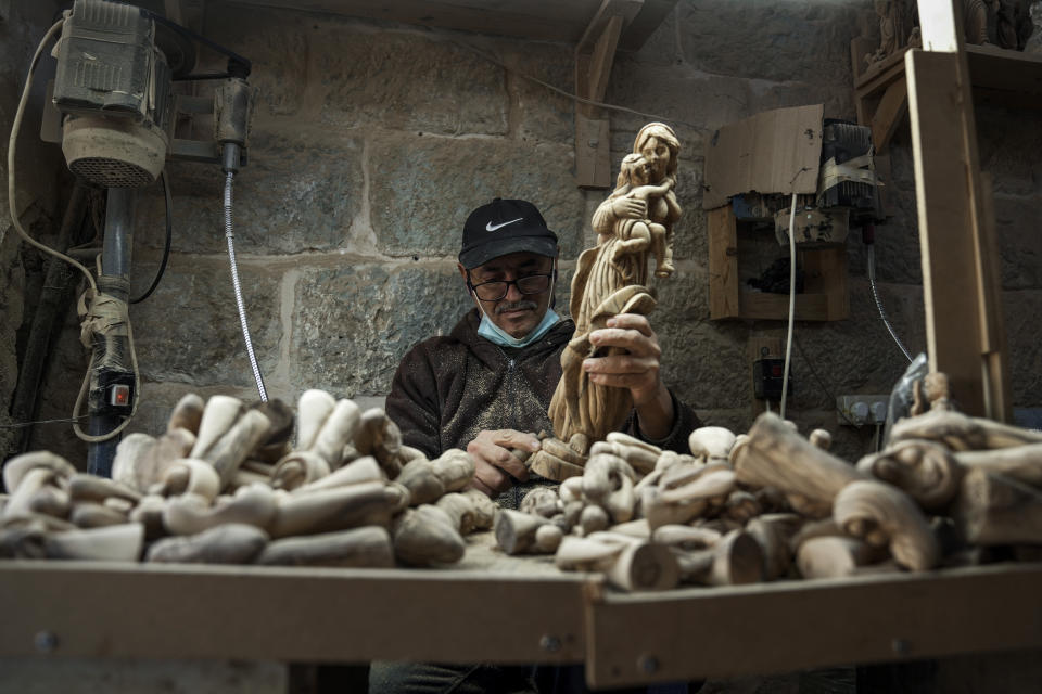 A Palestinian craftsman carves a figurine of the Virgin Mary and baby Jesus, in the West Bank town of Bethlehem, at the beginning of the Christmas season, Saturday, Dec. 3, 2022. Business in Bethlehem is looking up this Christmas as the traditional birthplace of Jesus recovers from a two-year downturn during the coronavirus pandemic. Streets are already bustling with visitors, stores and hotels are fully booked and a recent jump in Israeli-Palestinian fighting appears to be having little effect on the vital tourism industry. (AP Photo/ Mahmoud Illean)