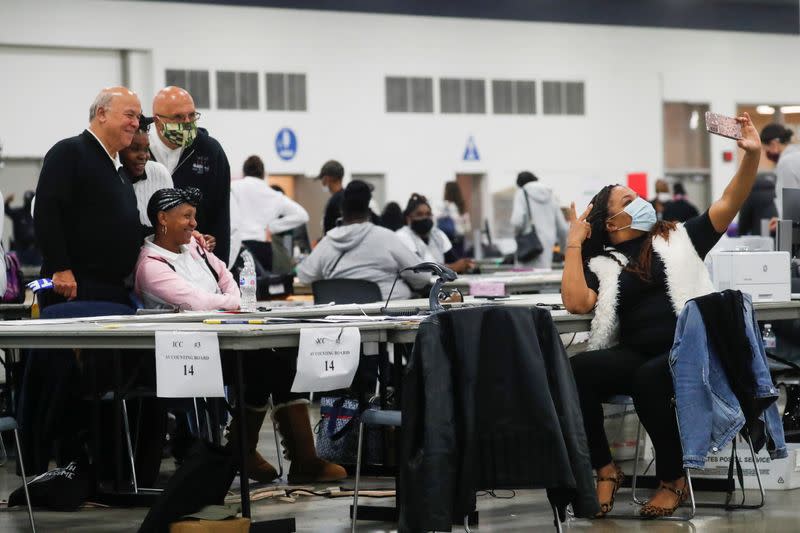 Poll workers pose as votes continue to be counted at the TCF Center the day after the 2020 U.S. presidential election, in Detroit, Michigan