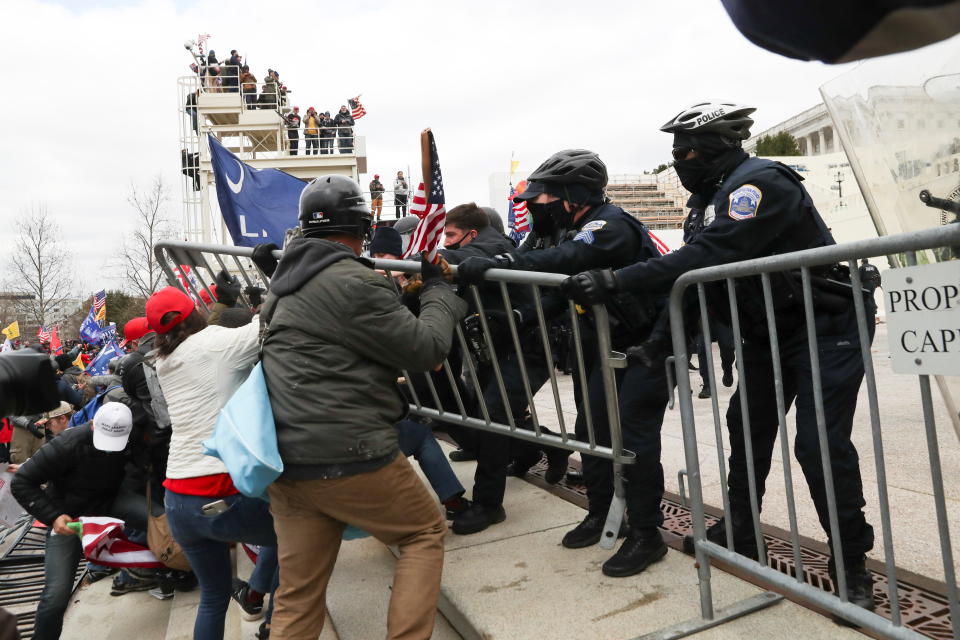 Donald Trump supporters breach temporary fencing while clashing with police at the US Capitol building.