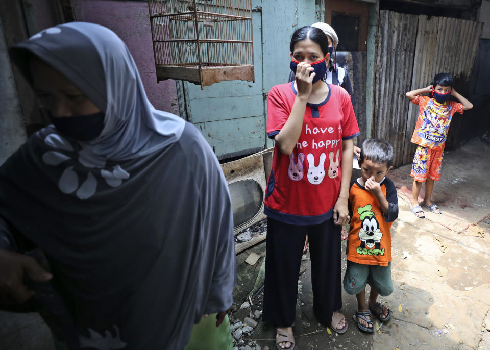 People cover their nose and mouth as workers fumigate their neighborhood to prevent a dengue fever outbreak in a slum in Jakarta, Indonesia, Wednesday, April 22, 2020. While 2019 was the worst year on record for global dengue cases, experts fear an even bigger surge is possible because their efforts to combat it were hampered by restrictions imposed during the coronavirus pandemic. (AP Photo/Dita Alangkara)
