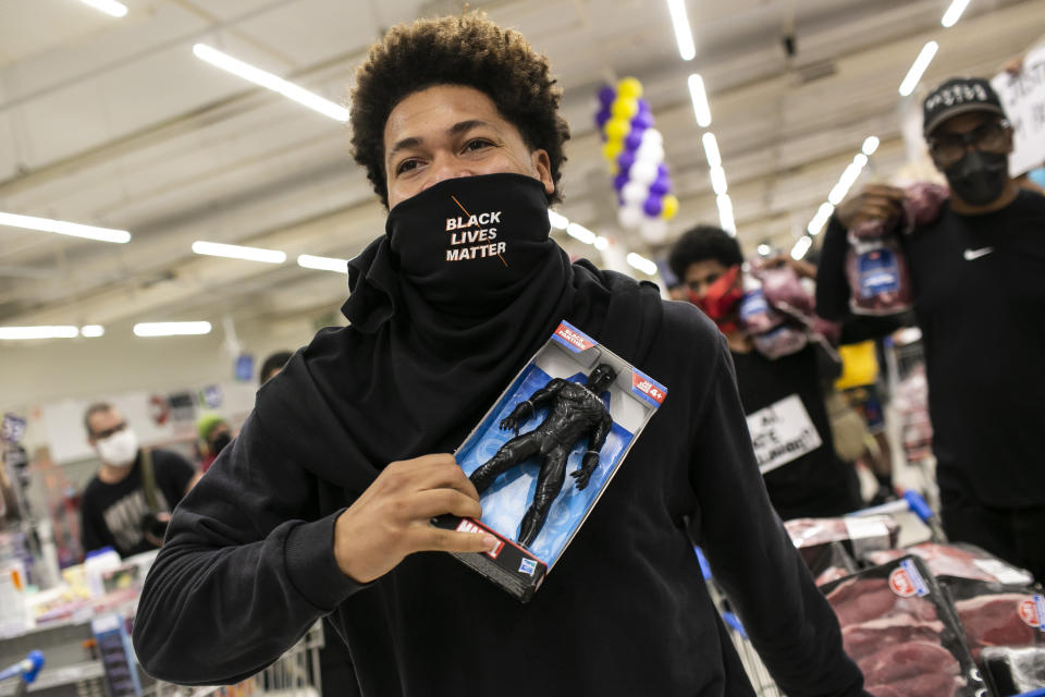 A Black Lives Matter activist holds a Black Panther doll inside a Carrefour supermarket during a demonstration against the murder of Black man Joao Alberto Silveira Freitas at a different Carrefour the night before, on Brazil's National Black Consciousness Day in Rio de Janeiro, Brazil, Friday, Nov.20, 2020. Freitas died after being beaten by supermarket security guards in the southern Brazilian city of Porto Alegre, sparking outrage as videos of the incident circulated on social media. (AP Photo/Bruna Prado)