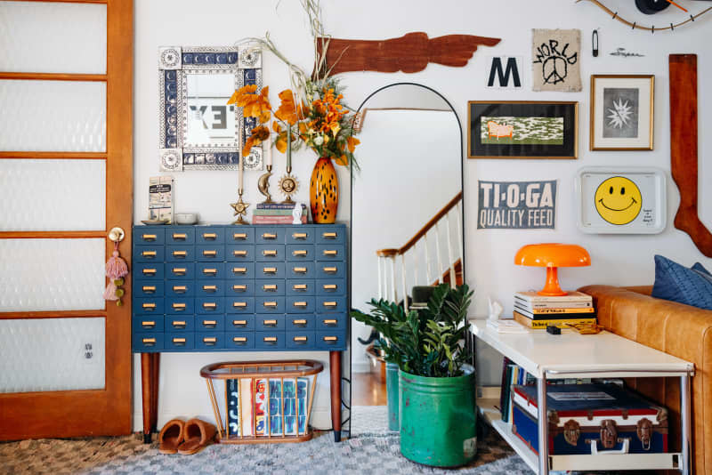 Blue card catalog cabinet and art-filled wall in living room.