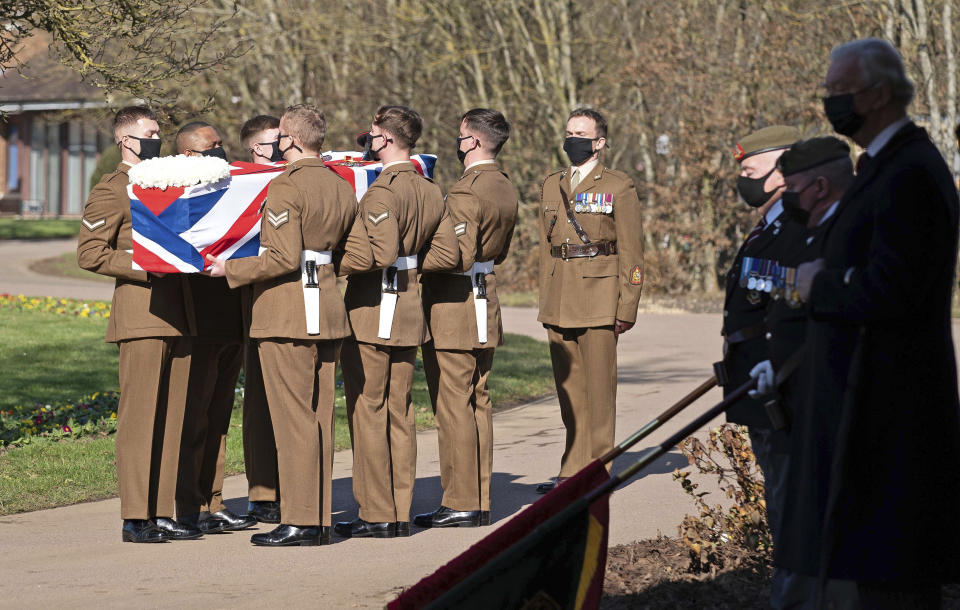 The coffin of Captain Tom Moore is carried by members of the Armed Forces during his funeral, at Bedford Crematorium, in Bedford, England, Saturday, Feb. 27, 2021. Tom Moore, the 100-year-old World War II veteran who captivated the British public in the early days of the coronavirus pandemic with his fundraising efforts died, Tuesday Feb. 2, 2021. (Joe Giddens/Pool Photo via AP)