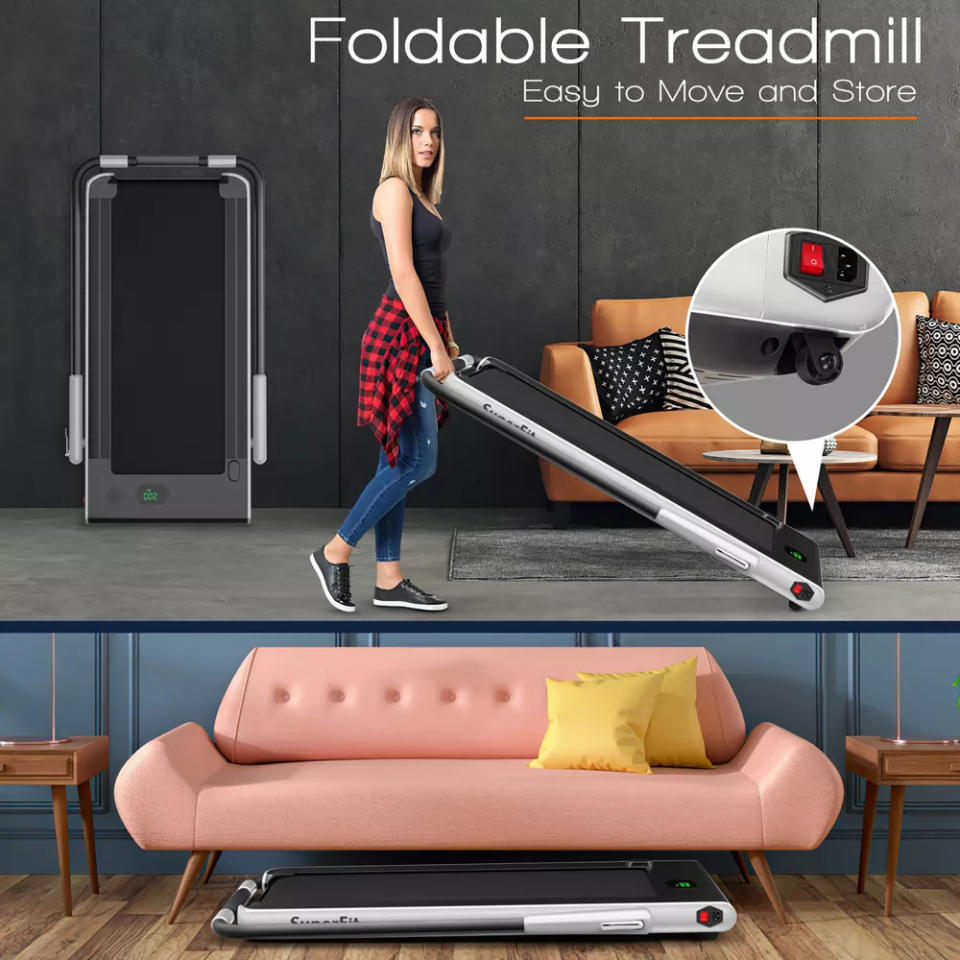 Foldable treadmill being moved by an individual in a living room, demonstrating its compact storage under a sofa