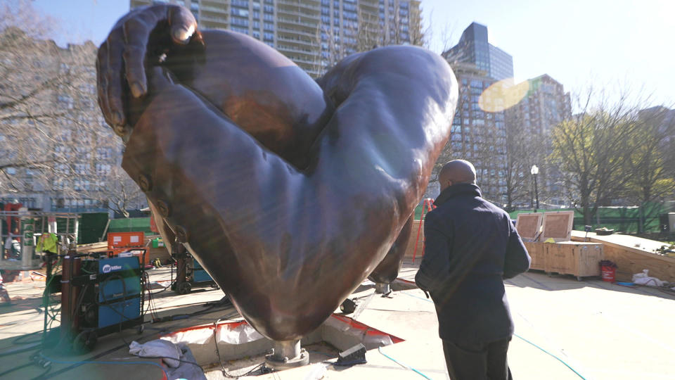 Artist Hank Willis Thomas watches the installation of his sculpture 
