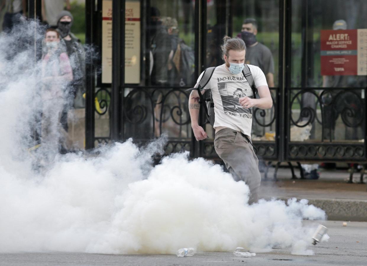 A protester kicks a tear gas canister back toward police during racial injustice protests May 28, 2020 in downtown Columbus that resulted from the murder of George Floyd by Minneapolis police officer Derek Chauvin.