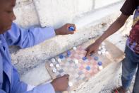 Children play checkers with plastic bottle caps in Canaan, on the outskirts of Port-au-Prince