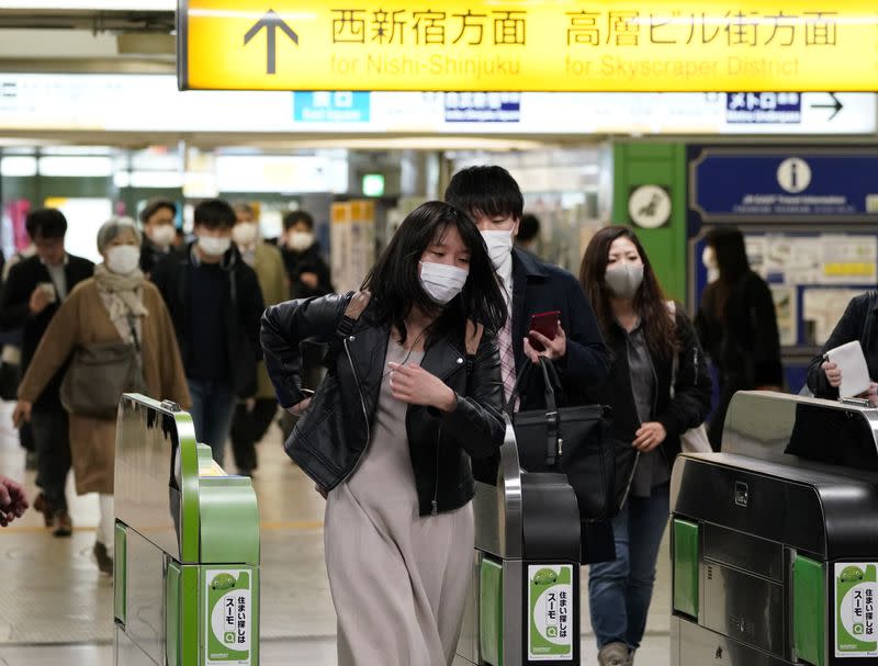 Passengers wearing protective masks go through turnstiles at Shinjuku station, following an outbreak of the coronavirus disease (COVID-19), in Tokyo