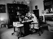 <p>Princess Elizabeth's office space in the Royal Sitting Room in the '40s featured a crystal chandelier, an elegant vase of white flowers, and glass trinkets on the shelves.</p>